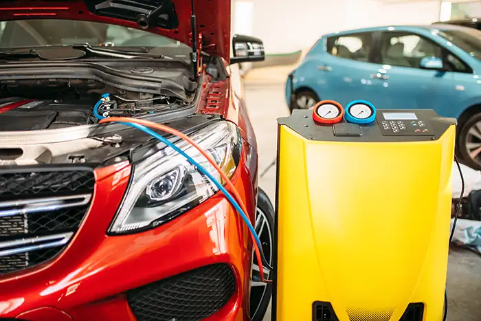 Equipo de recarga de aire acondicionado conectado a un automóvil en el taller.