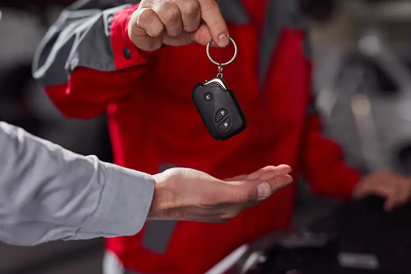 Mecánico entregando las llaves de un coche al cliente en un taller de reparación.