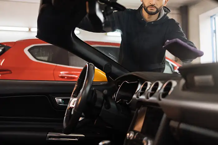 Especialista instalando un parabrisas nuevo en un automóvil en el taller.